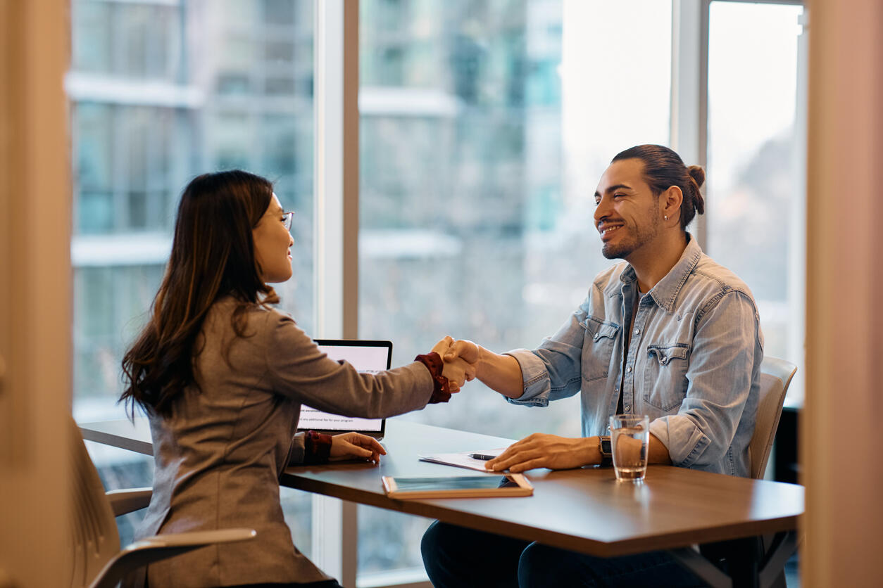 man and woman shaking hands over desk