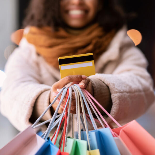 girl holding shopping bags with credit/debit card smiling