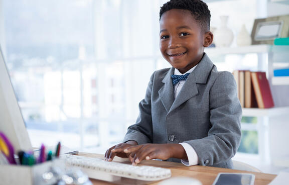 small child wearing a suit working on a computer