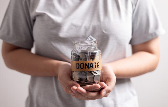 women holding a jar full of money marked donaitons. 